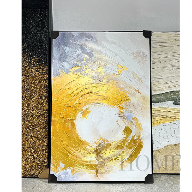 A modern abstract oil painting featuring swirls of gold and white with hints of other colors, framed in a simple black frame.